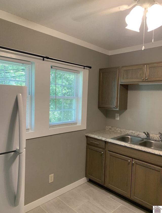 kitchen with light tile patterned floors, white refrigerator, and sink