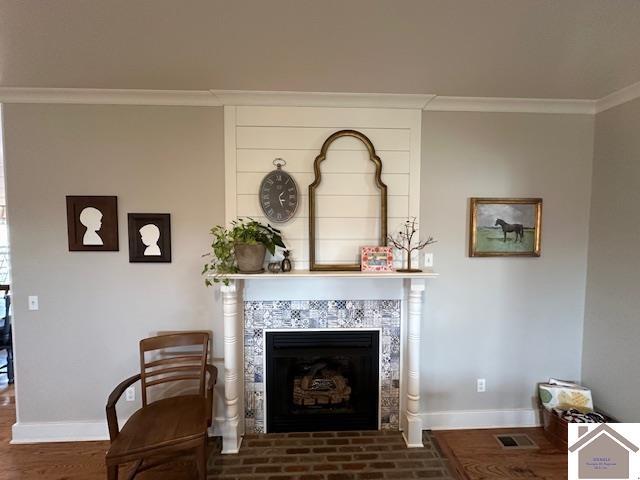 living area with a tile fireplace, crown molding, and dark hardwood / wood-style floors