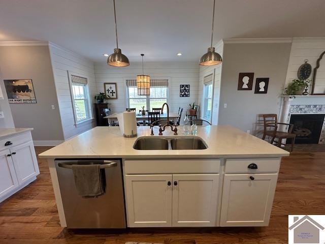 kitchen featuring a kitchen island with sink, sink, white cabinetry, decorative light fixtures, and stainless steel dishwasher