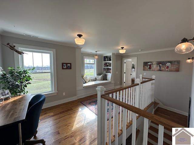 hallway with hardwood / wood-style floors, ornamental molding, and a healthy amount of sunlight