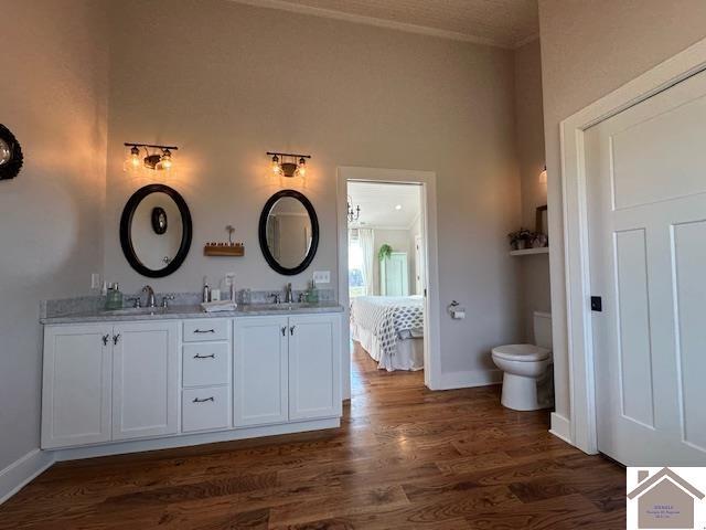 bathroom with toilet, crown molding, vanity, and wood-type flooring