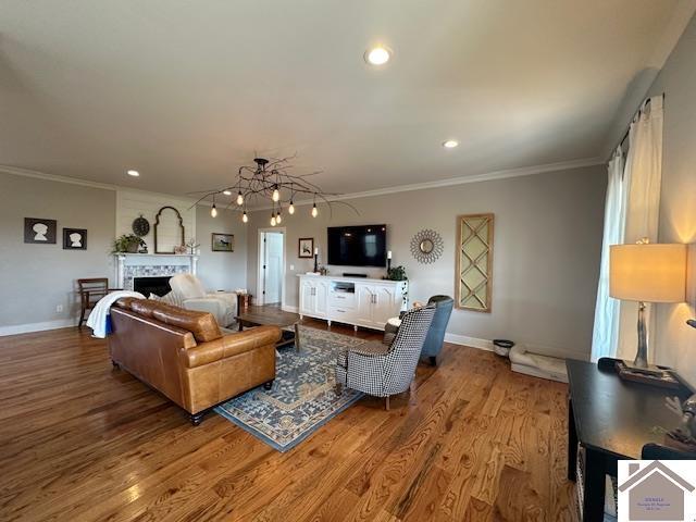 living room featuring wood-type flooring, ornamental molding, and a notable chandelier