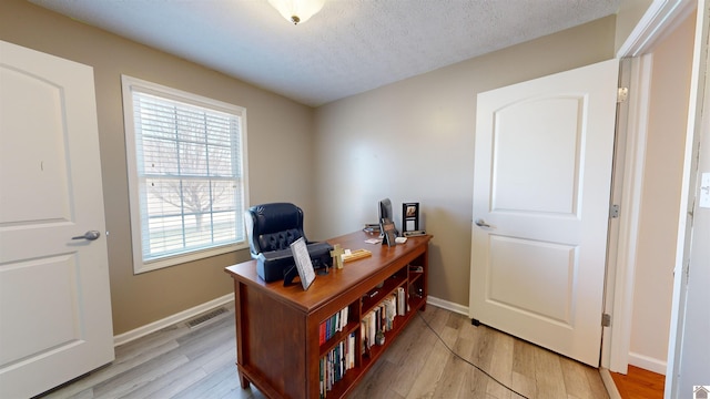 home office featuring a textured ceiling and light hardwood / wood-style flooring