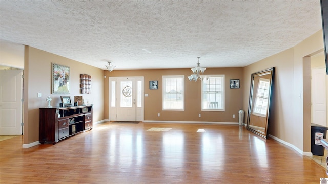 interior space featuring a textured ceiling, a chandelier, and light wood-type flooring