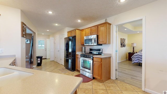 kitchen with stainless steel appliances, a textured ceiling, and light tile patterned floors