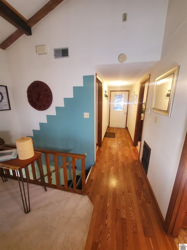 hallway with wood-type flooring and vaulted ceiling with beams