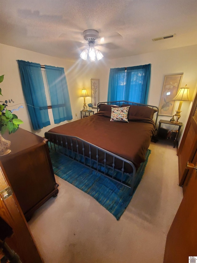 bedroom with carpet floors, ceiling fan, and a textured ceiling