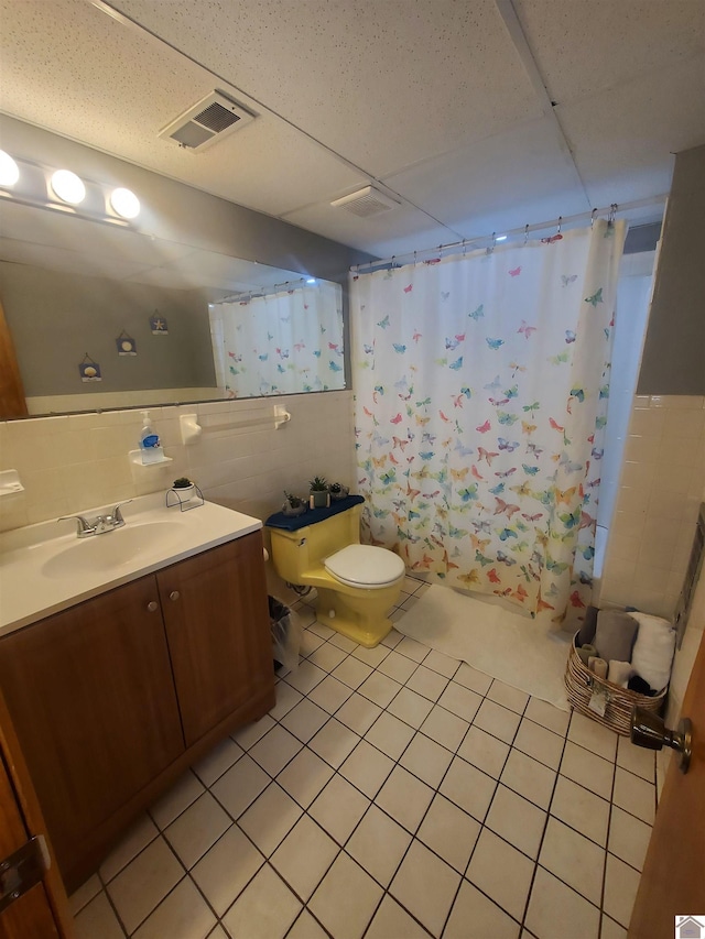 full bathroom with shower / tub combo, toilet, a paneled ceiling, tile patterned floors, and tile walls