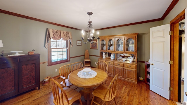 dining space with a chandelier, crown molding, and light hardwood / wood-style flooring