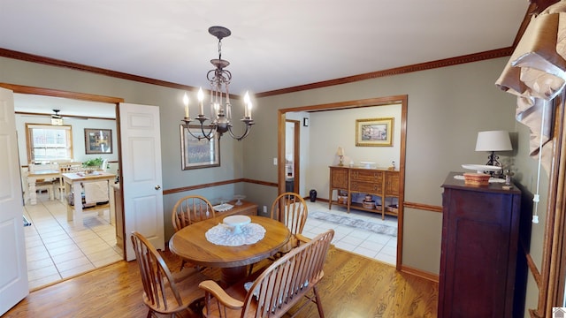 dining area with light hardwood / wood-style floors, ornamental molding, and a chandelier