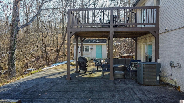 view of patio with central air condition unit, area for grilling, a wooden deck, and an outdoor structure