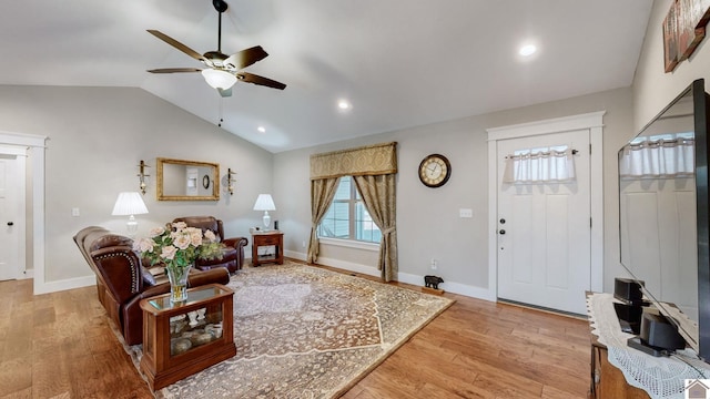 living room with light hardwood / wood-style floors, ceiling fan, and vaulted ceiling