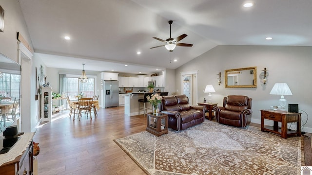 living room with ceiling fan, light hardwood / wood-style flooring, and vaulted ceiling