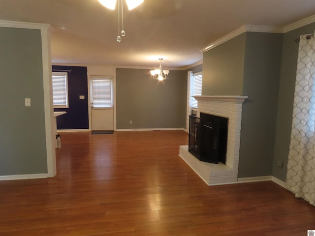 unfurnished living room with a chandelier, a brick fireplace, crown molding, and dark hardwood / wood-style floors