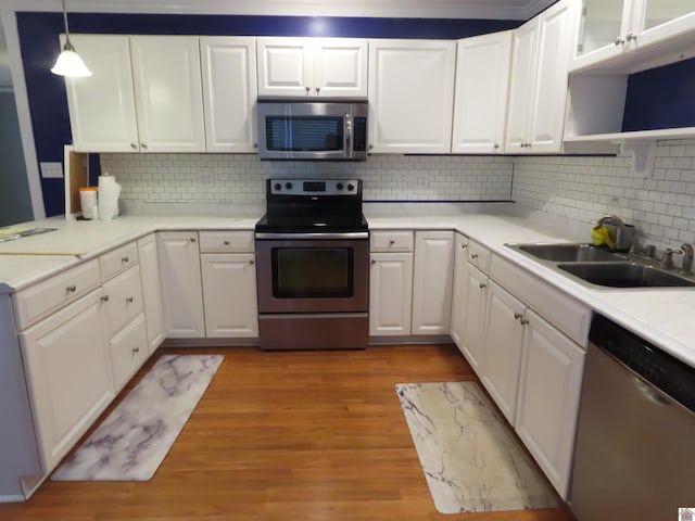 kitchen with appliances with stainless steel finishes, white cabinets, decorative light fixtures, and sink