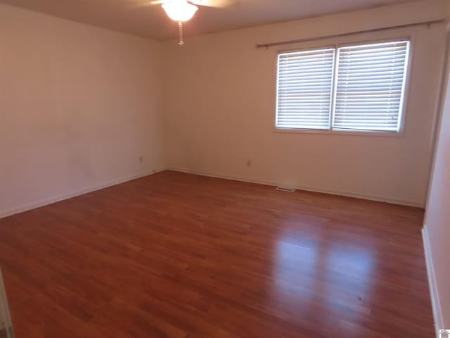 empty room with ceiling fan and dark hardwood / wood-style floors