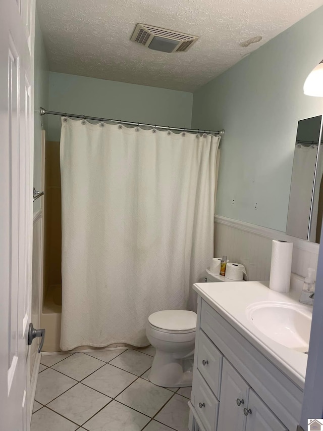 full bathroom featuring toilet, tile patterned floors, vanity, and a textured ceiling