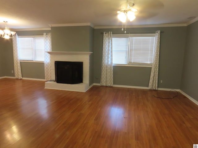 unfurnished living room featuring ceiling fan with notable chandelier, wood-type flooring, ornamental molding, and a wealth of natural light