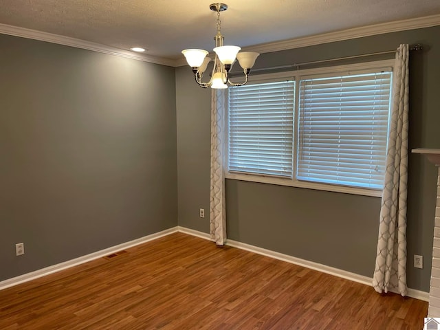 empty room featuring hardwood / wood-style flooring, an inviting chandelier, ornamental molding, and a textured ceiling