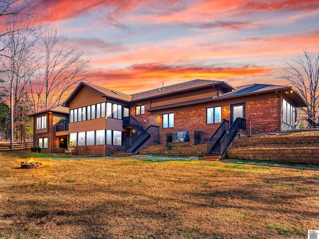 back house at dusk with a sunroom and a yard