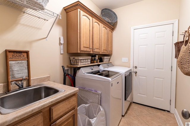 laundry area with light tile patterned floors, washer and clothes dryer, sink, and cabinets