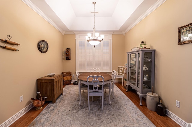 dining room featuring a tray ceiling, dark hardwood / wood-style floors, crown molding, and an inviting chandelier