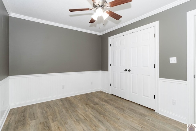 unfurnished bedroom with light wood-type flooring, ceiling fan, ornamental molding, and a closet