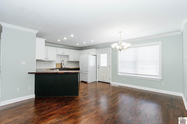 kitchen with kitchen peninsula, tasteful backsplash, white refrigerator, pendant lighting, and white cabinets