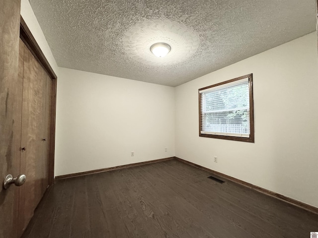 unfurnished bedroom with dark wood-type flooring, a textured ceiling, and a closet