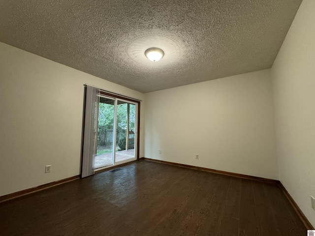 empty room with dark wood-type flooring and a textured ceiling