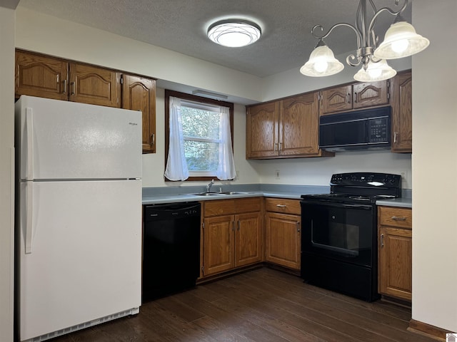 kitchen featuring an inviting chandelier, black appliances, dark wood-type flooring, pendant lighting, and sink