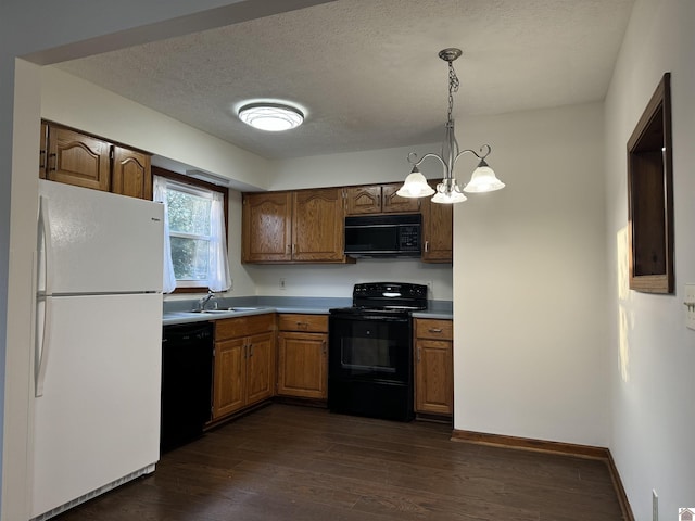 kitchen featuring black appliances, an inviting chandelier, hanging light fixtures, dark wood-type flooring, and a textured ceiling