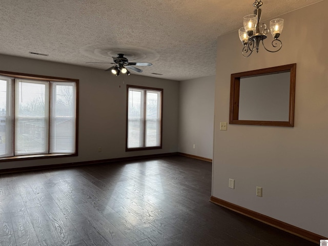 empty room featuring dark wood-type flooring, ceiling fan with notable chandelier, and a textured ceiling