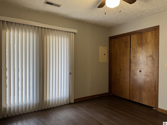 unfurnished bedroom with ceiling fan, a closet, dark wood-type flooring, and a textured ceiling