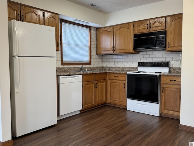 kitchen featuring backsplash, sink, white appliances, dark wood-type flooring, and a textured ceiling