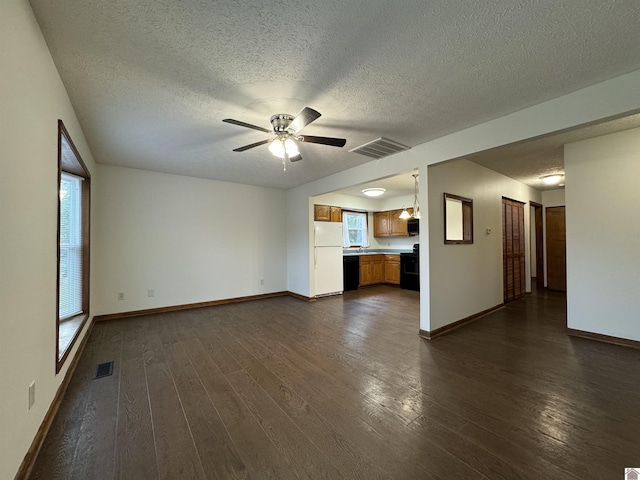 unfurnished living room with a textured ceiling, dark wood-type flooring, and ceiling fan