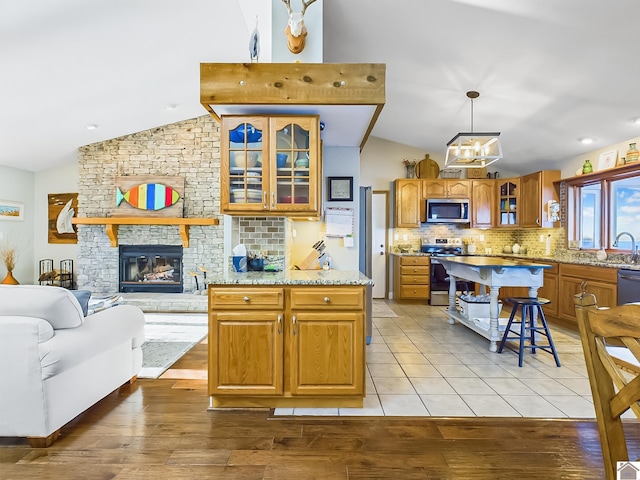 kitchen featuring appliances with stainless steel finishes, decorative backsplash, light hardwood / wood-style floors, and hanging light fixtures