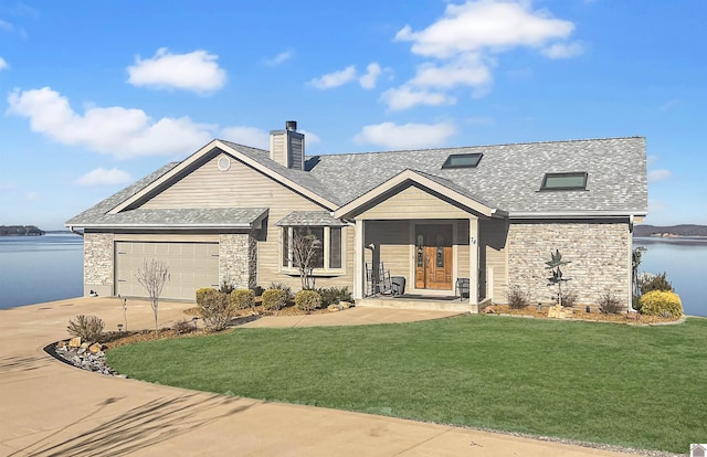 view of front facade with a garage, a front yard, and a water view