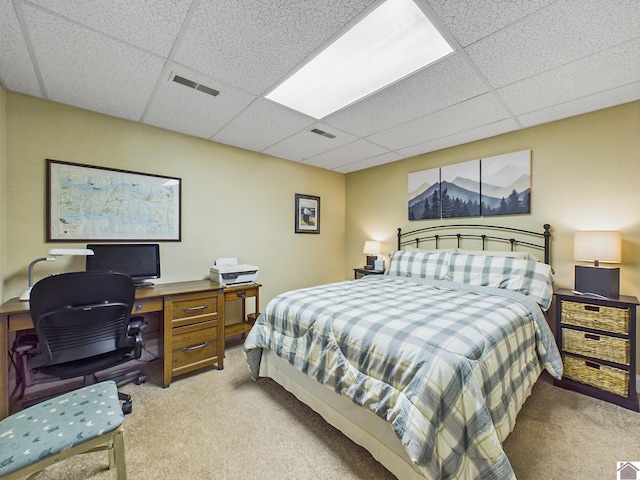 bedroom featuring light carpet and a drop ceiling