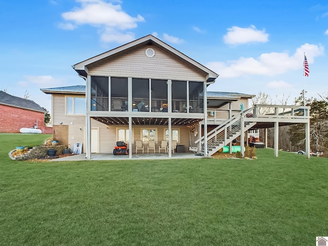 rear view of property with a wooden deck, a sunroom, a lawn, and a patio