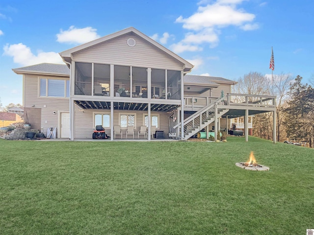 rear view of house featuring a lawn, a fire pit, a patio area, a sunroom, and a deck