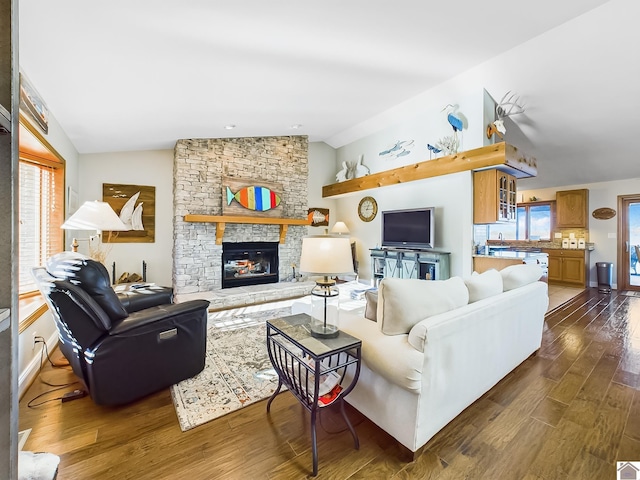 living room featuring a fireplace, a wealth of natural light, dark hardwood / wood-style flooring, and vaulted ceiling