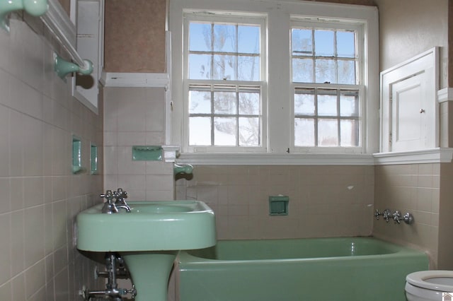 bathroom with toilet, tile walls, and a wealth of natural light