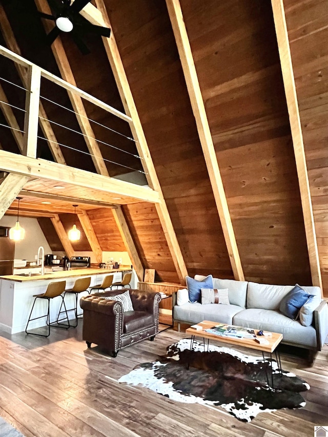 interior space with hardwood / wood-style floors, beamed ceiling, wooden walls, sink, and high vaulted ceiling