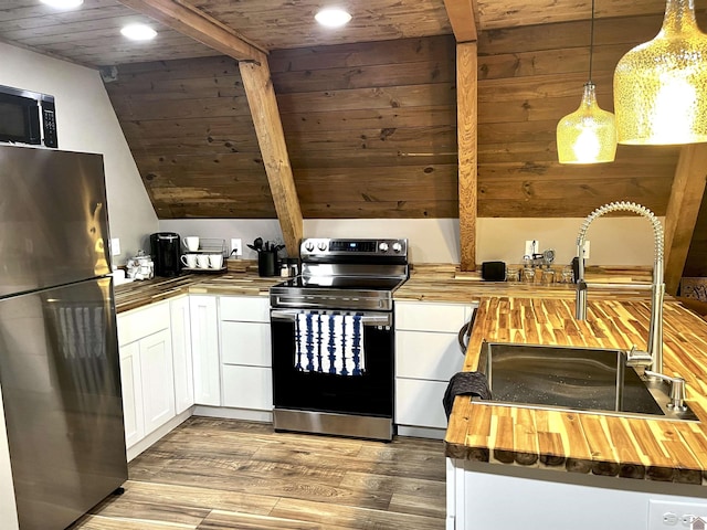 kitchen with pendant lighting, white cabinets, appliances with stainless steel finishes, butcher block counters, and sink