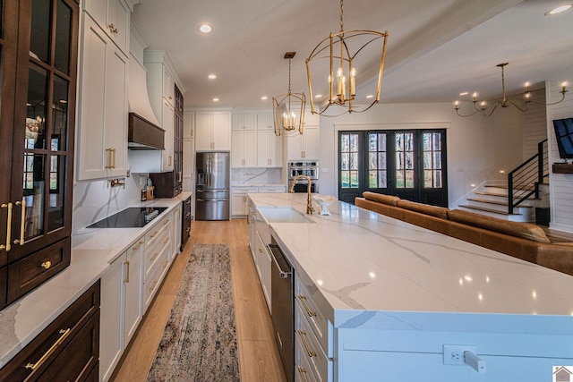 kitchen with a large island, appliances with stainless steel finishes, decorative backsplash, hanging light fixtures, and white cabinets