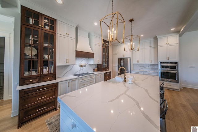 kitchen with decorative backsplash, custom exhaust hood, a spacious island, and sink