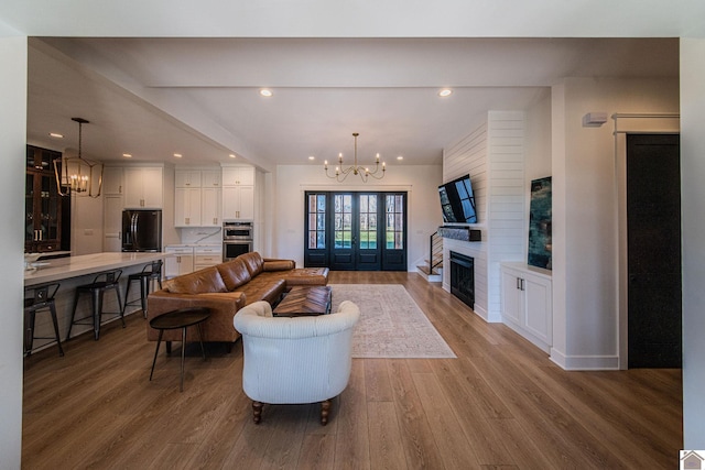 living room featuring wood-type flooring, an inviting chandelier, and a fireplace