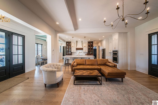 living room with light wood-type flooring, french doors, and beamed ceiling