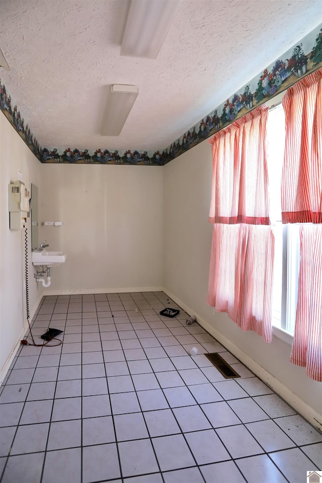 tiled empty room with sink and a textured ceiling